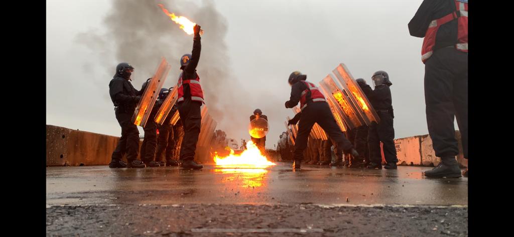 A group of police officers demonstrating the use of their riot gear against flammables