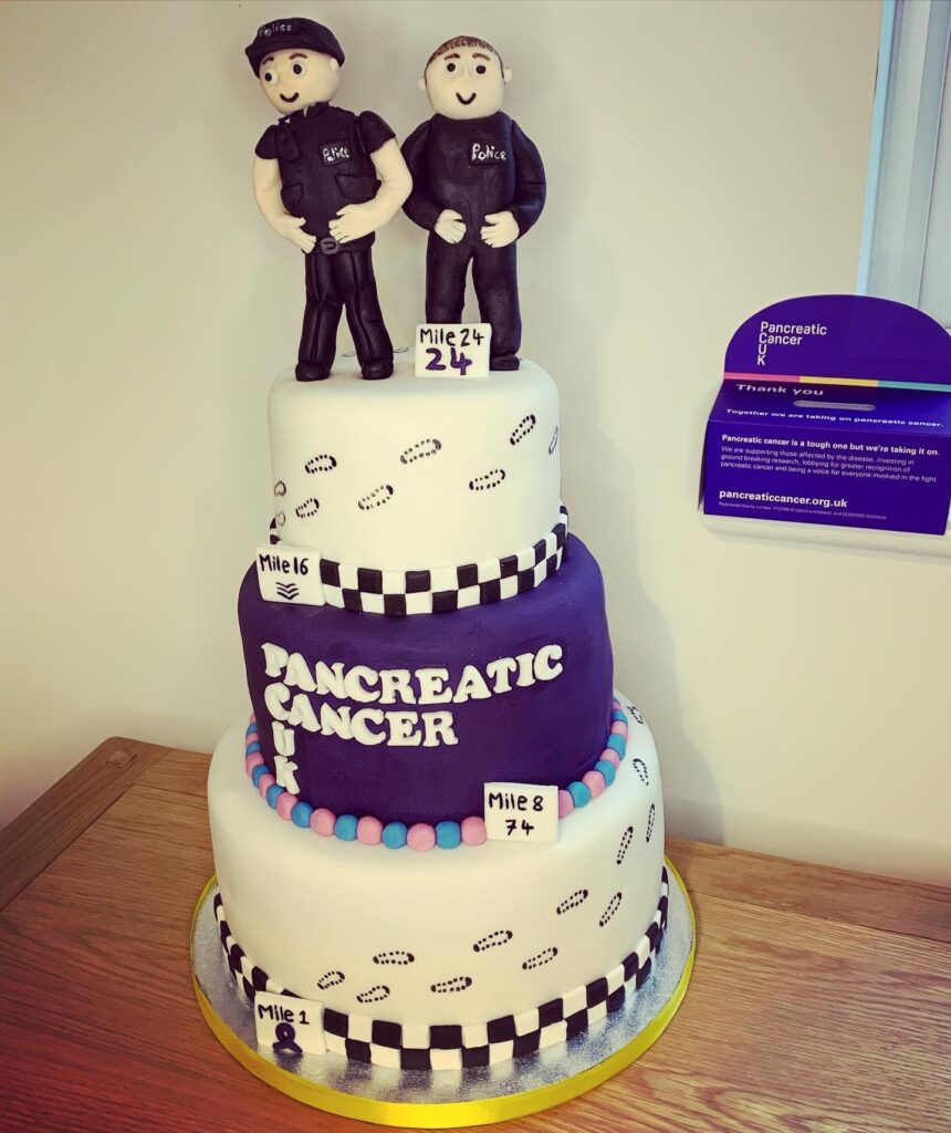 A three-tiered police themed cake with 2 models on top rewarded after completing the 24th mile