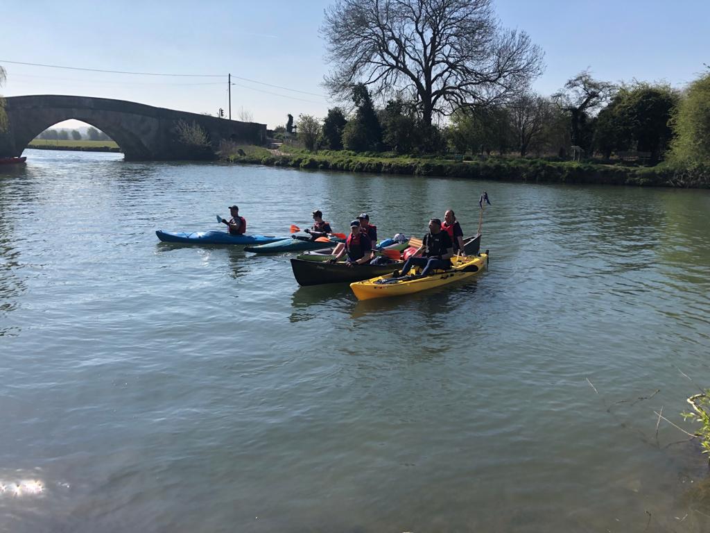 A group of people in 4 kayaks on the River Thames.